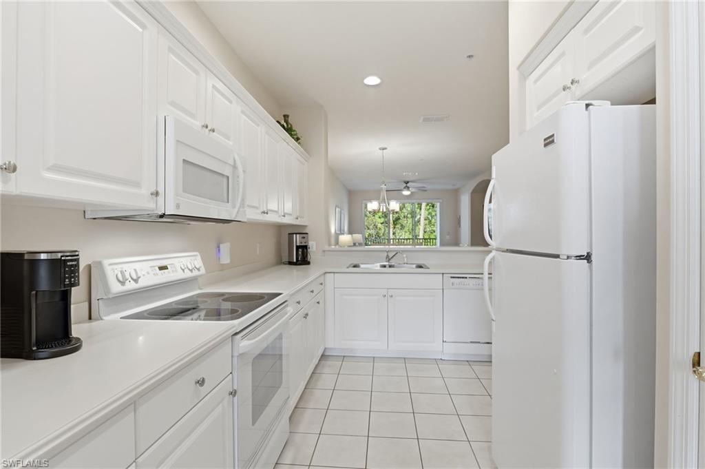 4873 Hampshire Court, Unit 104 Naples, FL 34112 - Photo 14 of 43 a kitchen with white cabinets and white appliances