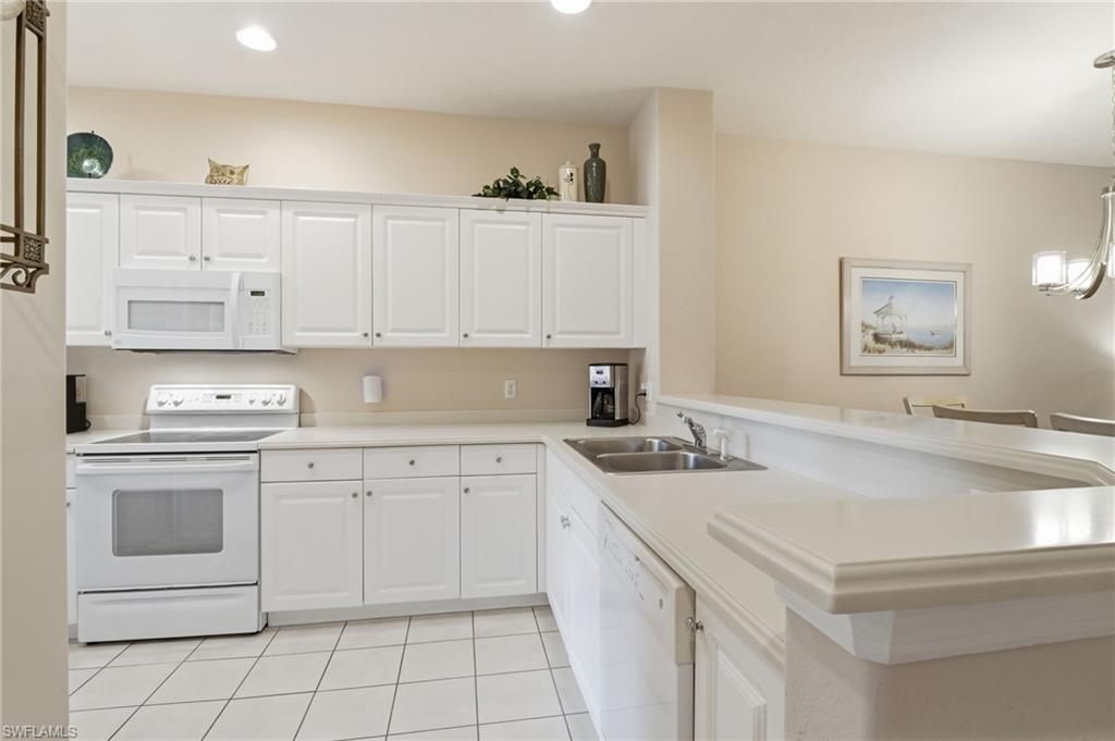 4873 Hampshire Court, Unit 104 Naples, FL 34112 - Photo 16 of 43 a kitchen with a sink stove and cabinets
