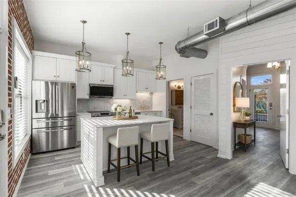 a kitchen with stainless steel appliances kitchen island granite countertop a dining table chairs and a refrigerator