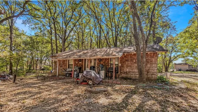 a view of a wooden house with large trees and wooden fence