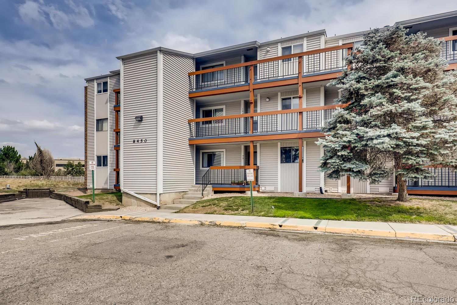 a front view of a building with a garden and trees