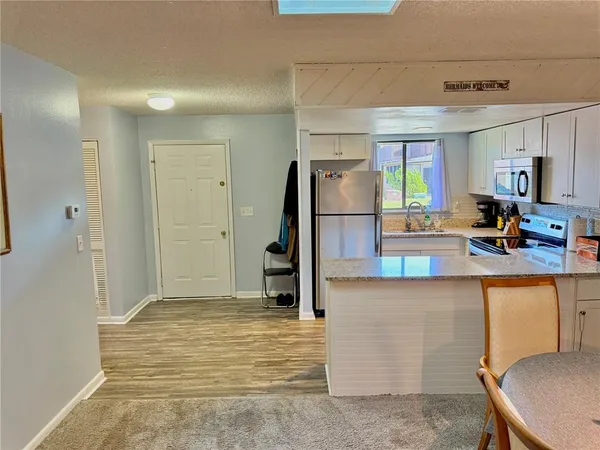 a kitchen with stainless steel appliances granite countertop a refrigerator a stove and a wooden floors