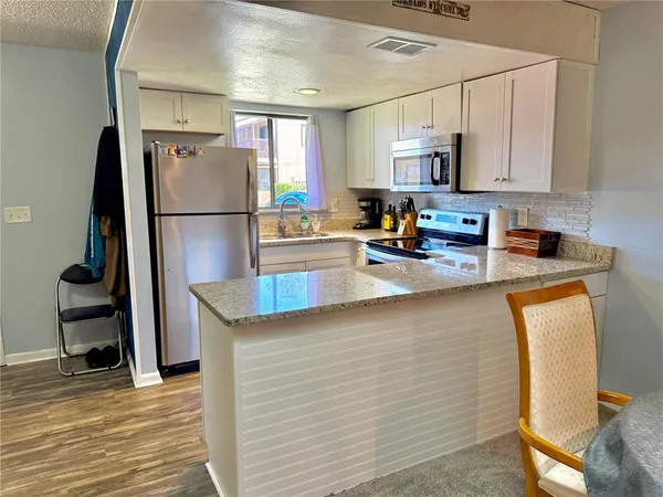 a kitchen with stainless steel appliances granite countertop a refrigerator a stove a sink a microwave a counter space and cabinets