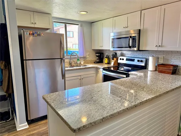 a kitchen with granite countertop a stove and a refrigerator