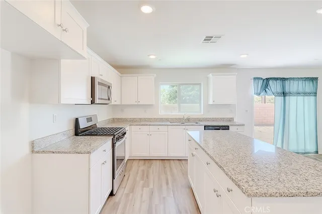 a kitchen with stainless steel appliances granite countertop a stove top oven a sink dishwasher and a refrigerator with wooden floor