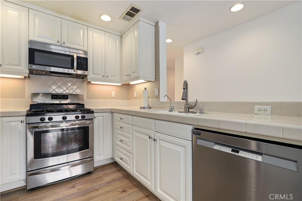 28364 Mirabelle Lane Saugus, CA 91350 - Photo 7 of 32 a kitchen with stainless steel appliances white cabinets a sink and a stove