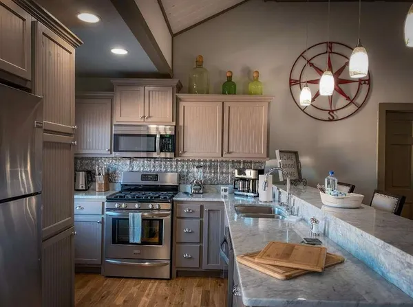 a kitchen with stainless steel appliances granite countertop a stove a sink dishwasher and a refrigerator with wooden floor