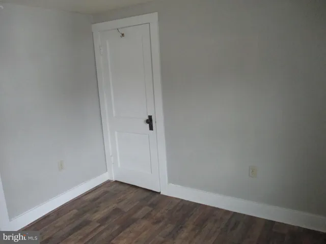 an empty room with wooden floor windows and fan