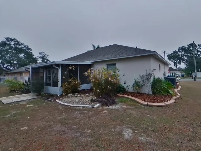 a backyard of a house with table and chairs under an umbrella