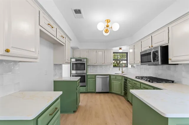 a kitchen with kitchen island stainless steel appliances sink stove microwave and cabinets