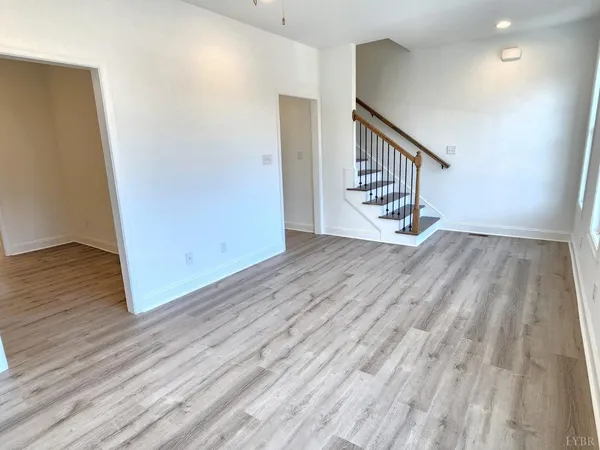 a view of an empty room with wooden floor and stairs