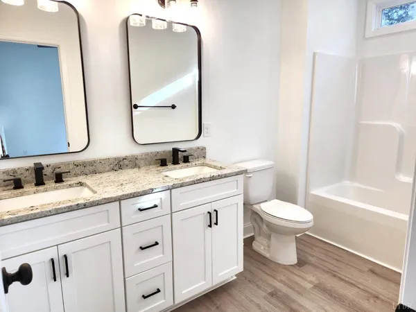 a bathroom with double vanity sinks a toilet a vanity and a mirror