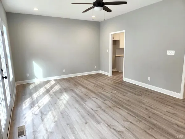 an empty room with wooden floor and windows
