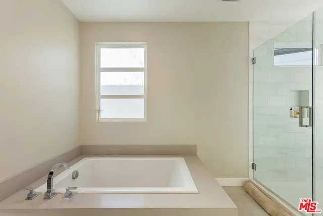a bathroom with a granite countertop tub a double vanity sink and a large mirror