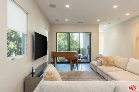 a living room with furniture a flat screen tv and a large window