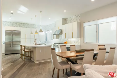 a kitchen with a dining table chairs and white cabinets