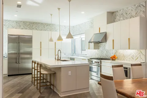 a room with stainless steel appliances kitchen island granite countertop a sink a stove and a wooden floors