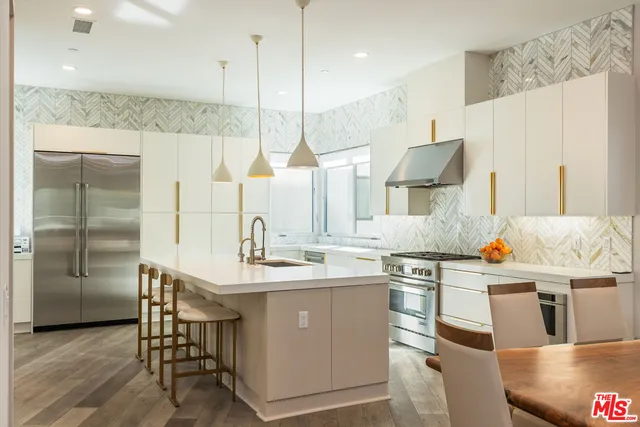 a room with stainless steel appliances kitchen island granite countertop a sink a stove and a wooden floors