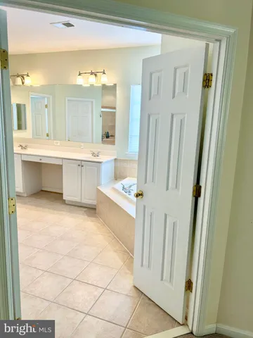 a large bathroom with a double vanity sink a mirror and a bathtub
