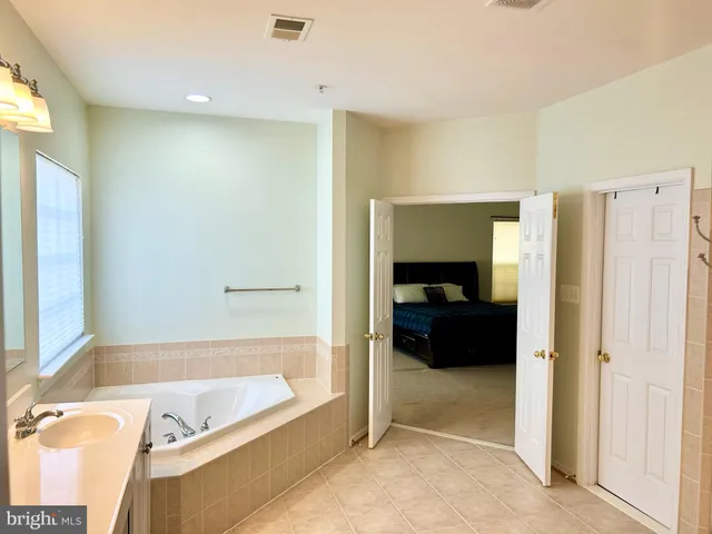 a bathroom with a tub a mirror and a shower