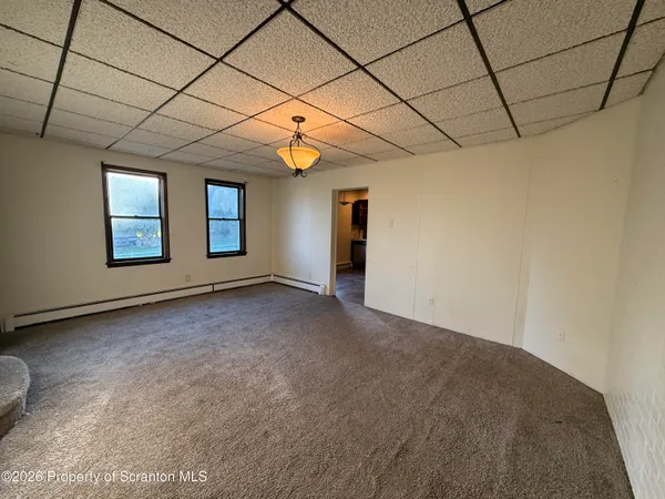 an empty room with windows and chandelier fan