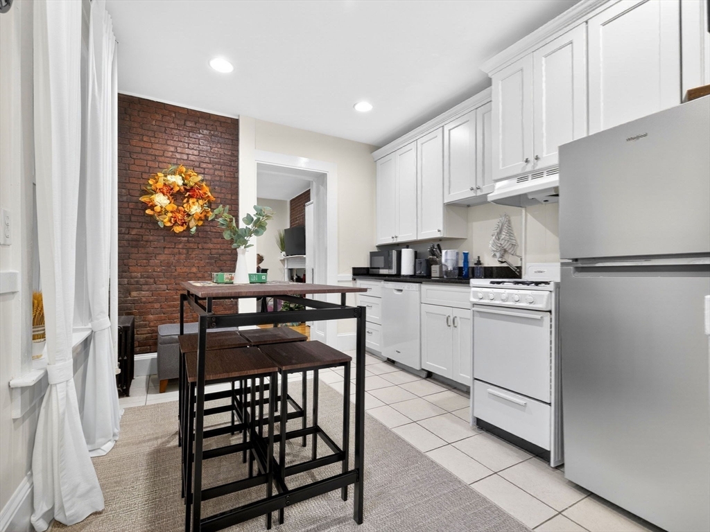 52 Temple Street Boston, MA 02114 - Photo 18 of 34 a kitchen with stainless steel appliances granite countertop a stove a refrigerator and a dining table with wooden floor