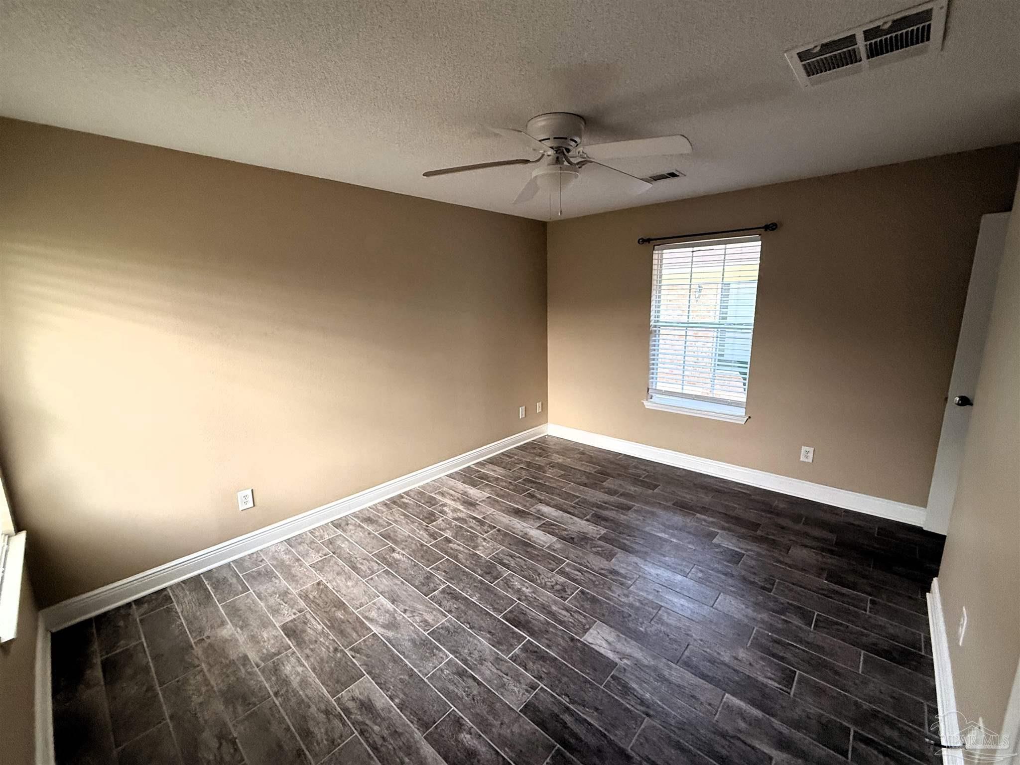 3055 Wallace Lake Road Pace, FL 32571 - Photo 25 of 33 an empty room with wooden floor fan and windows