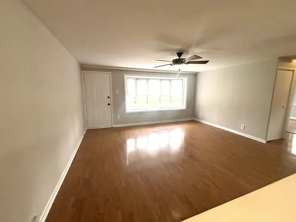 an empty room with wooden floor and windows