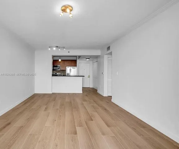 a view of a room with a kitchen and wooden floor