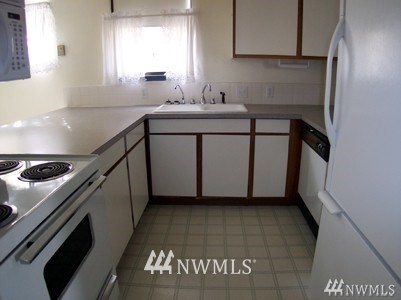 211 East 3rd Street Aberdeen, WA 98520 - Photo 21 of 27 a kitchen with a sink a stove top oven and cabinets