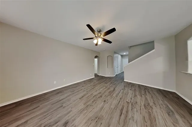 an empty room with wooden floor and ceiling fan