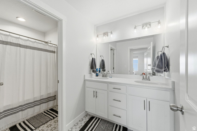 1038 South Old Towne Road Layton, UT 84041 - Photo 27 of 39 Bathroom featuring a dual vanity with white cabinetry, integrated sinks, and a large wall-mounted mirror