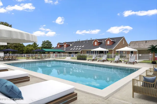 a view of a swimming pool with lawn chairs and a dining table under an umbrella
