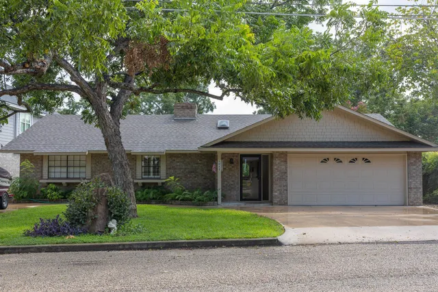 a front view of a house with a garden and trees