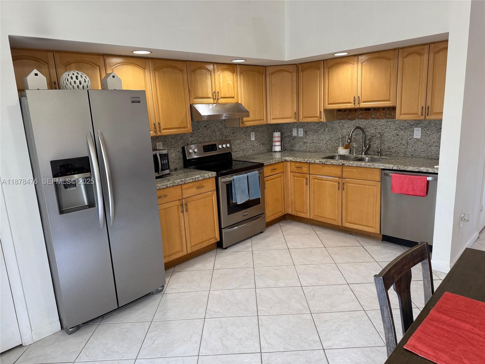 12413 Southwest 112th Terrace Miami, FL 33186 - Photo 5 of 16 a kitchen with stainless steel appliances granite countertop a refrigerator a sink a stove and island