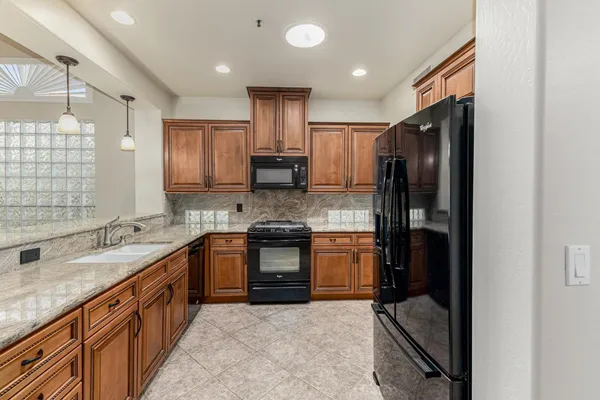 a large kitchen with stainless steel appliances granite countertop a refrigerator a sink and a stove
