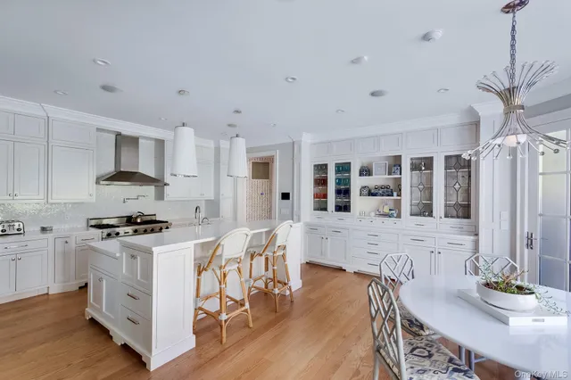 a kitchen with stainless steel appliances granite countertop a stove top oven a sink a dining table and chairs with wooden floor