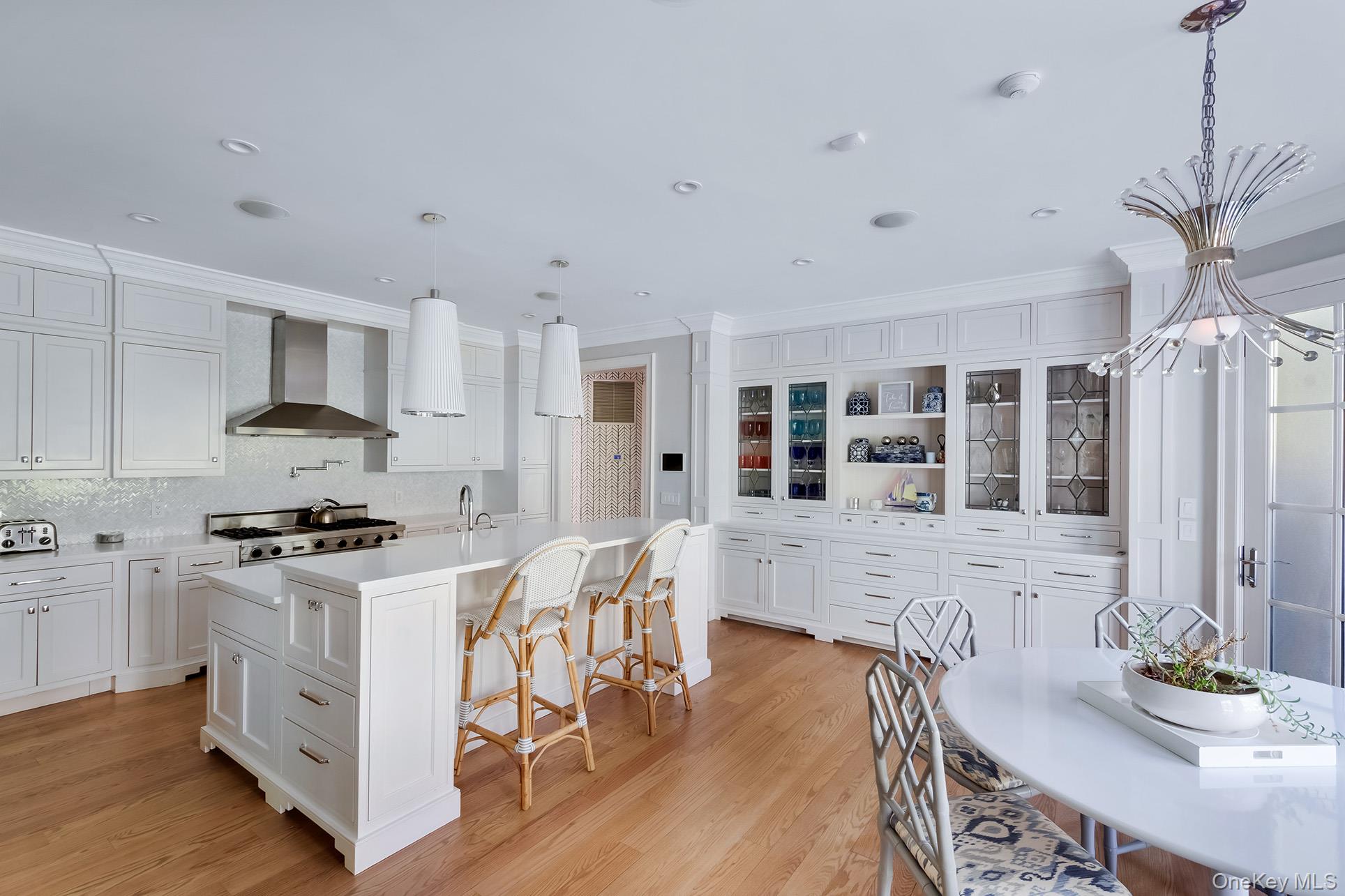 77 Jericho Road East Hampton, NY 11937 - Photo 10 of 31 a kitchen with stainless steel appliances granite countertop a stove top oven a sink a dining table and chairs with wooden floor