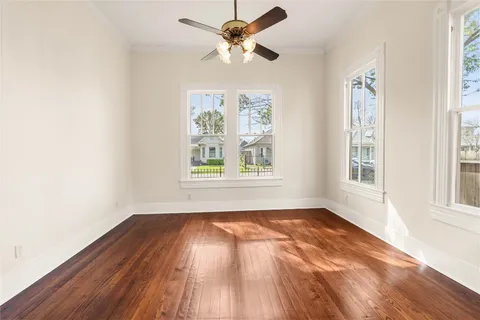 an empty room with wooden floor cabinet and windows