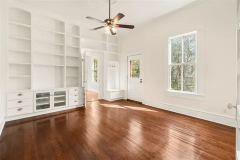 a view of an empty room with a window and wooden floor