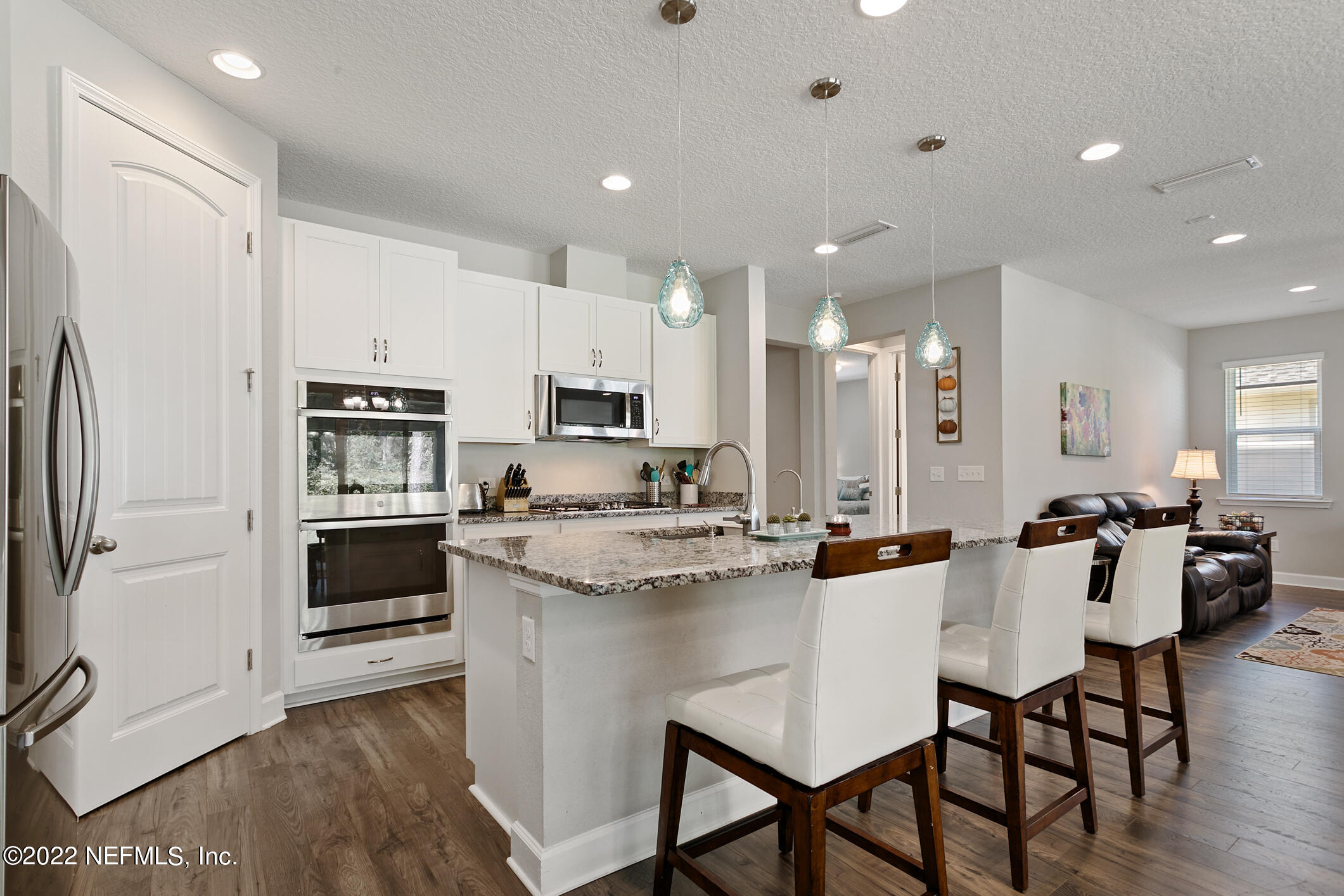 1098 Flach Drive St. Johns, FL 32259 - Photo 18 of 52 a kitchen with stainless steel appliances kitchen island granite countertop a stove a refrigerator a sink a stove and white cabinets with wooden floor