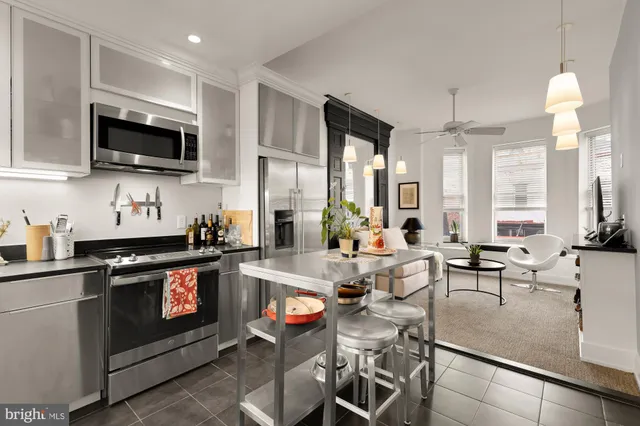 a kitchen with stainless steel appliances a stove a sink cabinets and a dining table
