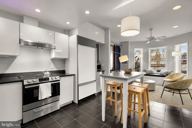 a kitchen with stainless steel appliances a stove a refrigerator island and chairs in it