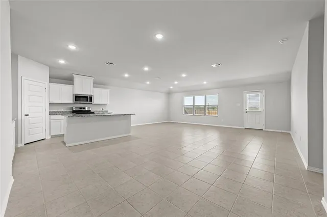 a view of an empty room with kitchen stove and refrigerator