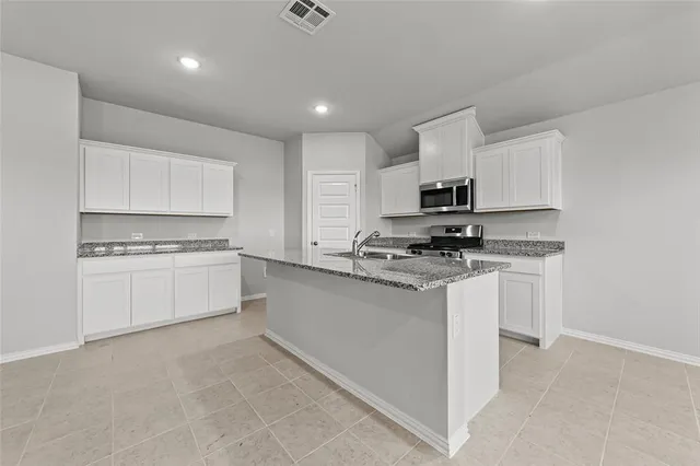 a kitchen with granite countertop white cabinets and stainless steel appliances
