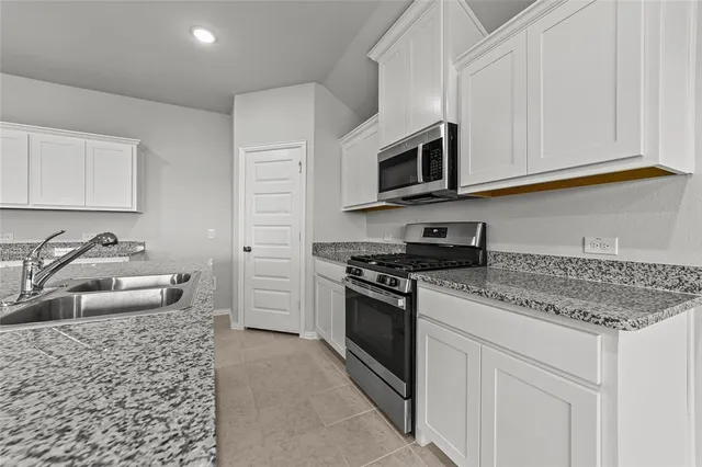 a kitchen with stainless steel appliances granite countertop a sink stove and microwave