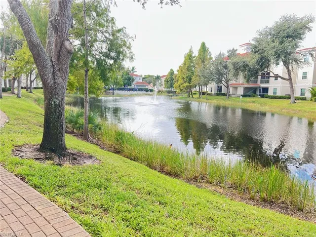 a view of a lake with a yard and large trees