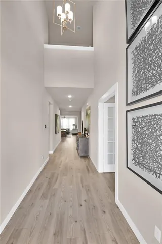 a view of a hallway with wooden floor and a chandelier