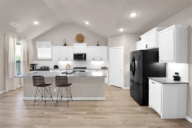 a kitchen with kitchen island white cabinets and stainless steel appliances