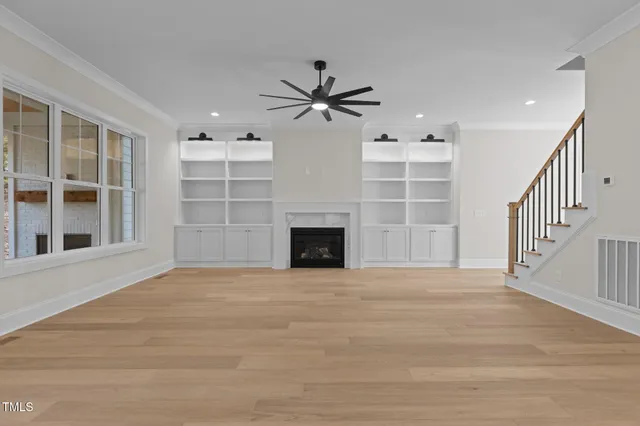 a view of an empty room with a window and kitchen view